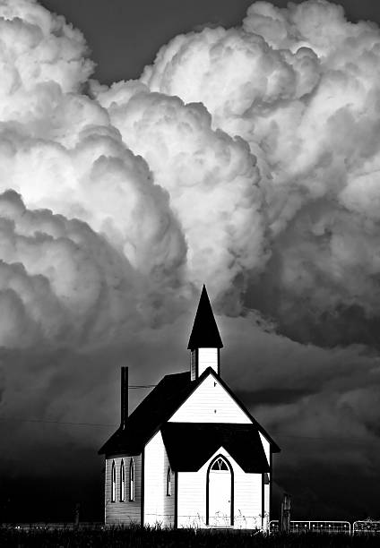 Thunderhead clouds forming behind a country church black and white